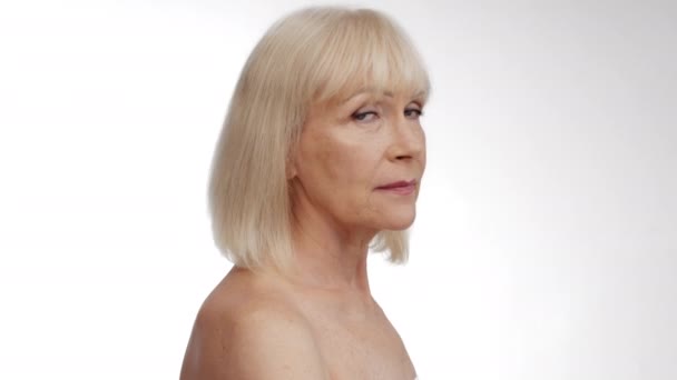 Beauty portret van volwassen goed verzorgde vrouw draaien gezicht naar de camera en glimlachen, poseren met blote schouders - Video