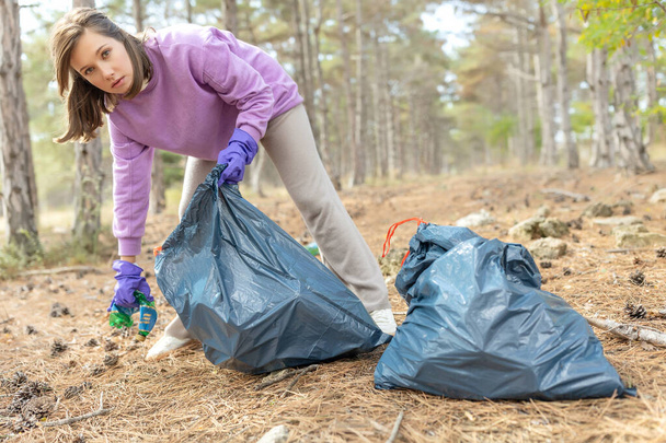 A woman removes rubbish in nature. - Φωτογραφία, εικόνα