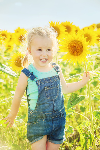 mooi meisje speelt met de zonnebloemen - Foto, afbeelding
