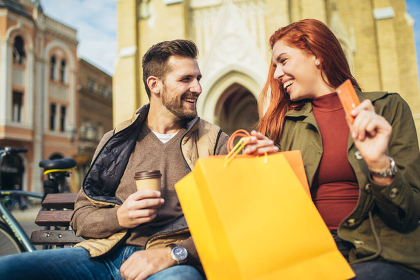 Porträt eines glücklichen Paares mit Einkaufstüten nach einem Einkauf in der Stadt, lächelnd und mit Kreditkarte - Foto, Bild
