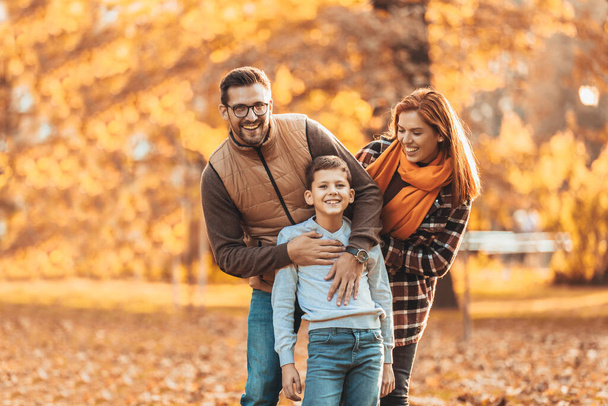 Πορτρέτο μιας ευτυχισμένης οικογένειας που διασκεδάζει στο πάρκο του φθινοπώρου. - Φωτογραφία, εικόνα