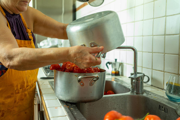 A woman preparing a tomato sauce in the kitchen - Foto, afbeelding