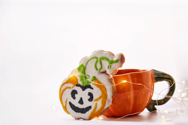 Halloween creative concept: pumpkin cup and homemade cute cookies in shape of cute pumpkins. Atmospheric aesthetic autumn mood or trick or treat concept. Copy space. Home cooking and coziness. Copy space - Photo, Image