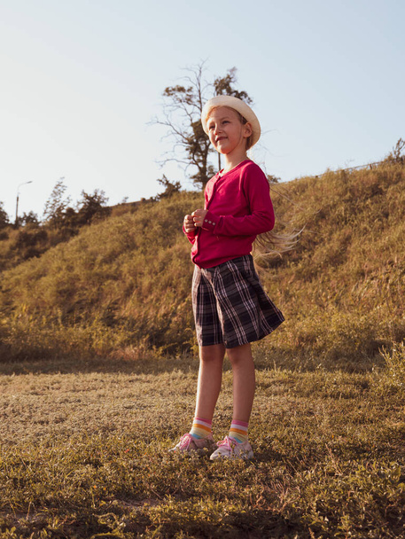 Šťastná holčička s dlouhými vlasy portrét skákání na přírodním pozadí větrný den. Roztomilý kluk, co chodí sám v podzimním parku. Hezké dítě v klobouku odpočinku Cestovní dovolená Svoboda životního stylu štěstí koncept - Fotografie, Obrázek