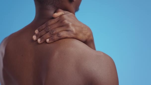Dolore muscolare. Uomo afroamericano muscoloso irriconoscibile che soffre di dolore alla spalla, massaggio e riscaldamento del collo - Filmati, video