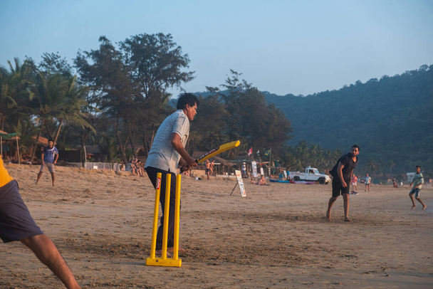 Grupo de adultos indios jugando al cricket en la playa al atardecer, Goa, India - Foto, Imagen
