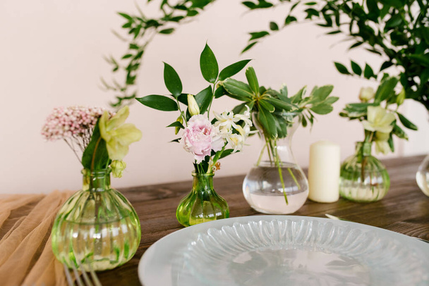 Monet lasiset maljakot, joissa on kukkia juhlapöydän asettamisessa. Valikoiva fokus - Valokuva, kuva