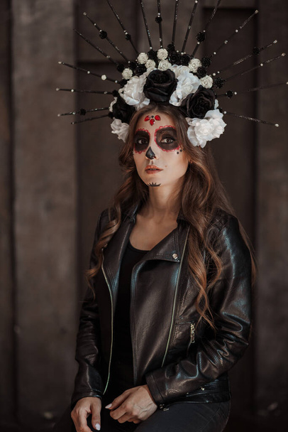 Mexican female in special black outfit wears white clay skull, professional makeup to look spooky - 写真・画像
