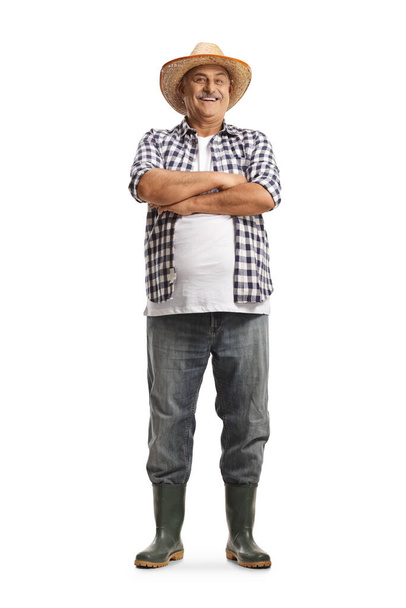 Full length portrait of a mature farmer smiling and posing with crossed arms isolated on white background - Фото, изображение