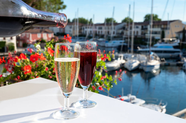 Summer party with kir royal cocktail, pouring of French brut champagne sparkling wine and creme cassis in glasses in yacht harbour of Port Grimaud near Saint-Tropez, French Riviera vacation, France - Fotoğraf, Görsel