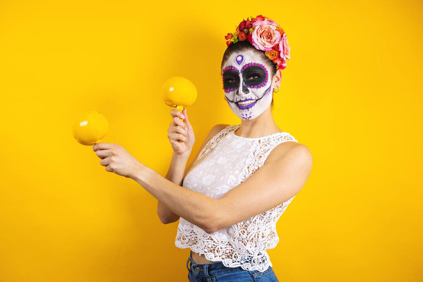 Mexican Catrina, portrait of young latin woman holding mexican maracas traditional rattle musical instrument,  Halloween party in Mexico - Photo, Image