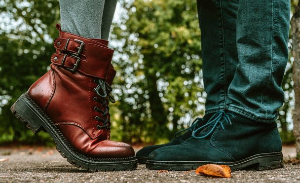 Egy pár lába. Férfiak és nők állnak egymással szemben. Egy közeli kép kék szarvasbőr cipőkről és bordó bőr csizmákról lábujjhegyen. Közelkép. - Fotó, kép