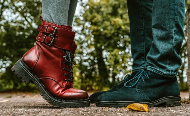Egy pár lába. Férfiak és nők állnak egymással szemben. Egy közeli kép kék szarvasbőr cipőkről és bordó bőr csizmákról lábujjhegyen. Közelkép. - Fotó, kép