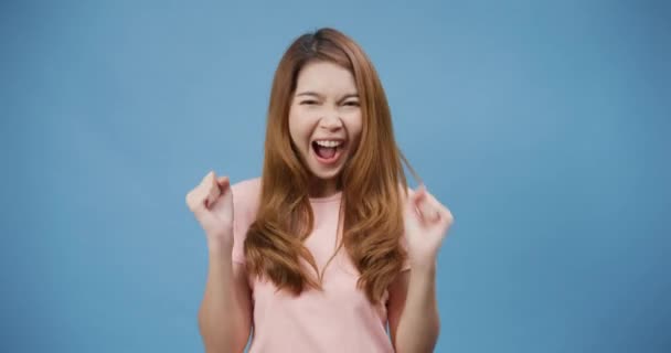 Fiatal ázsiai hölgy pozitív arckifejezéssel, vidám és izgatott, alkalmi ruhába öltözve, és a kamerát kék háttér felett nézi. Boldog imádnivaló boldog nő örül a sikernek. Az arckifejezés fogalma. - Felvétel, videó