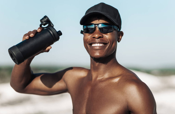 Smiling black man, Sportsman resting after running with a bottle of water, Rest after hard training in nature in the mountains, Sport concept, motivation, healthy lifestyle - Photo, image