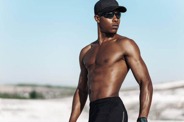 Portrait African American man, fitness athlete, with a muscular naked torso, on a sunny day outdoors in nature, sports, motivation, healthy lifestyle - Photo, Image