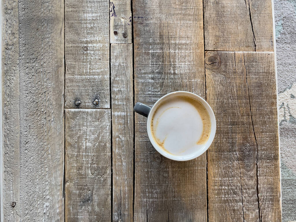 Ahşap bir masanın üzerindeki kafeden bir kahve. - Fotoğraf, Görsel