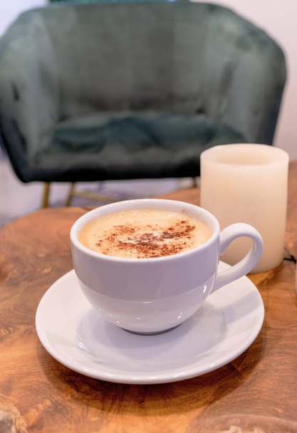 Un cappuccino avec mousse d'art sur une table avec une chaise verte.  - Photo, image