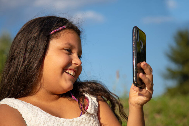 gipsy κορίτσι με μακριά μαύρα μαλλιά βγάζει selfies με το smartphone του - Φωτογραφία, εικόνα