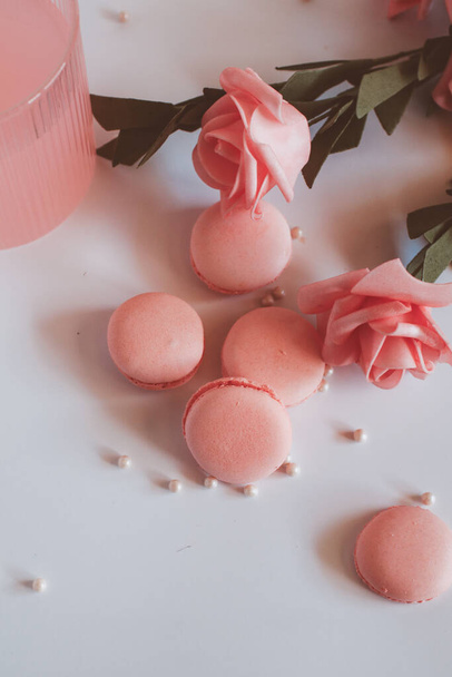 Pink macaroons with bouquet of rose on marble table, pastel colored, Traditional French multicolour macaroon. selective focus. Copy space - Foto, afbeelding