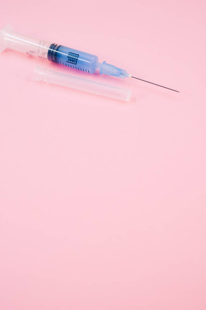 an isolated injection syringe on a pink background with text space - Fotó, kép