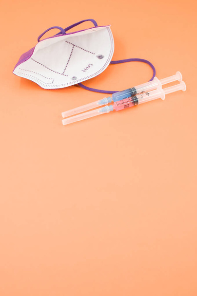 Isolated respiratory mask with syringe on an orange paper background wit text space - Photo, image