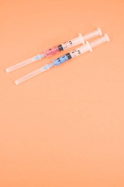 an isolated injection syringe on orange paper background with text space - Zdjęcie, obraz
