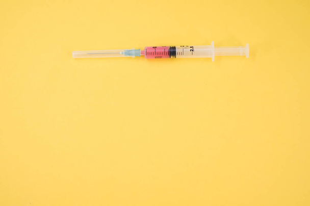 an isolated injection syringe on a yellow paper background with text space - Foto, Imagem
