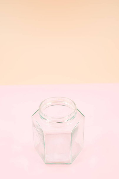 Empty glass jar isolated on a pink background with copy space - Фото, изображение