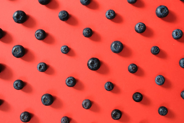 A pattern of blueberry fruit on red background - Foto, imagen