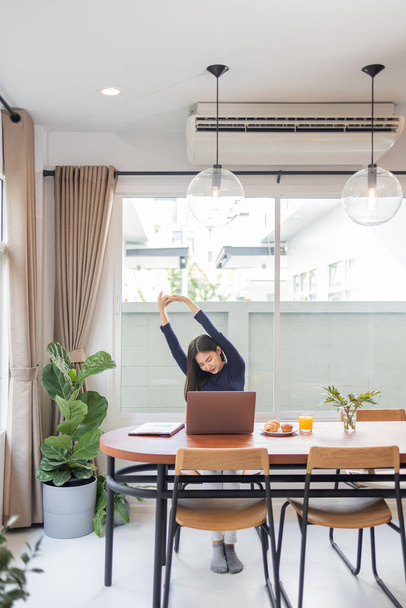 Trabajo desde casa concepto de una empresaria relajada estirando los brazos mientras trabaja remotamente en su casa. - Foto, imagen