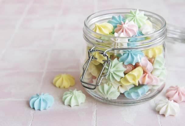 Pequenos merengues coloridos no frasco de vidro no fundo da telha rosa - Foto, Imagem
