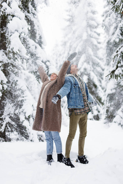 amore e divertimento invernale - ritratto di una giovane coppia felice che vomita neve in una foresta invernale - Foto, immagini