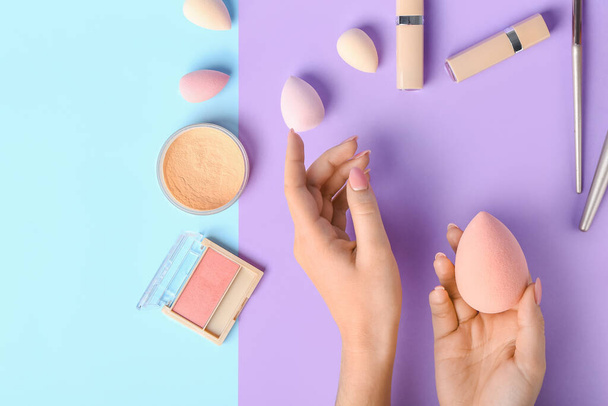 Female hands with stylish makeup sponge and decorative cosmetics on color background - Photo, Image
