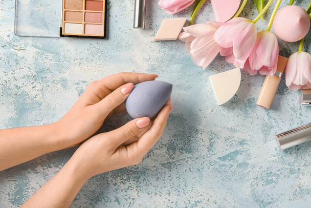 Vrouwelijke handen met stijlvolle make-up spons en decoratieve cosmetica op kleur achtergrond - Foto, afbeelding