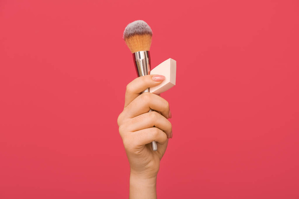 Female hand with stylish makeup sponge and brush on color background - Photo, Image