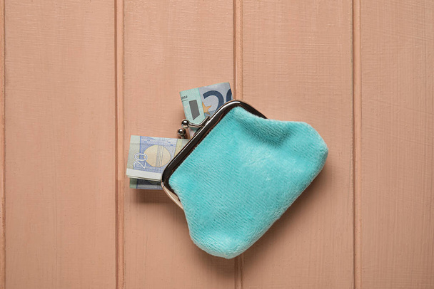 Μπλε πορτοφόλι με χαρτονομίσματα σε μπεζ ξύλινο φόντο - Φωτογραφία, εικόνα