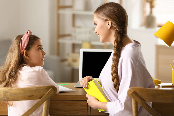 Κοριτσάκι με τη μητέρα της κάνουν μαθήματα στο σπίτι. - Φωτογραφία, εικόνα