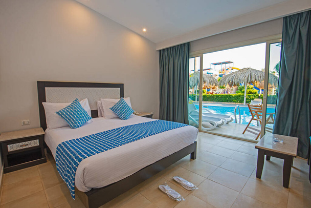 Double bed in suite of a luxury hotel room with terrace and pool view - Photo, Image
