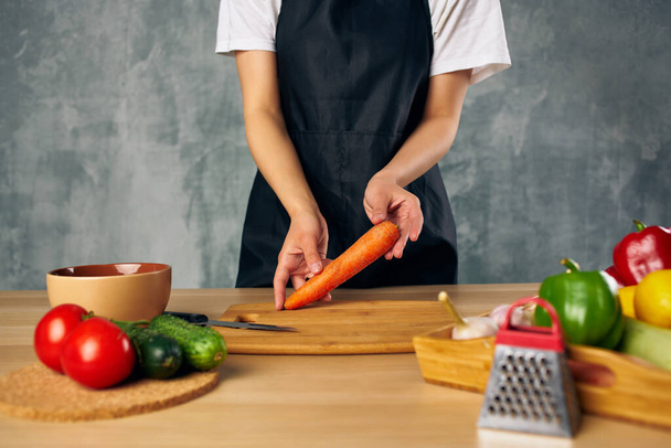 Woman in black apron lunch at home vegetarian food cutting board - Fotoğraf, Görsel