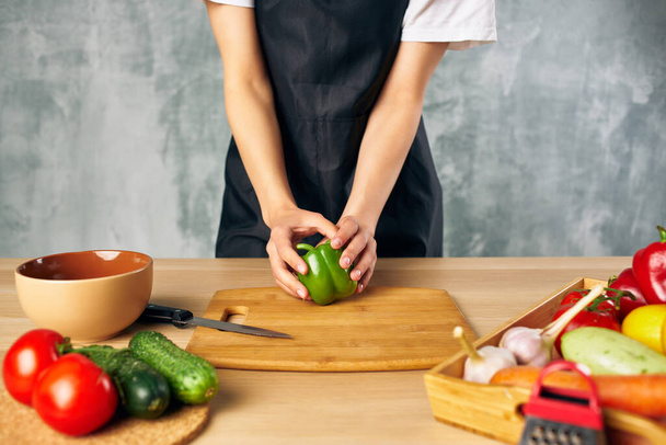 Főzőnő a konyhán zöldségeket vagdos - Fotó, kép