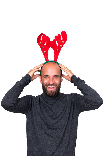 Smiling young caucasian man with Christmas reindeer antlers looking at camera. white background. Vertical image. - Photo, Image