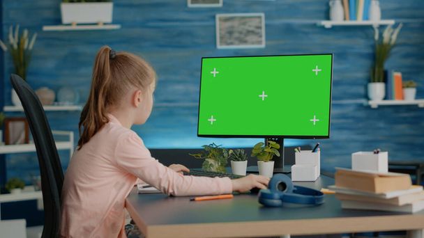 Školačka se dívá na počítač s horizontální zelenou obrazovkou - Fotografie, Obrázek