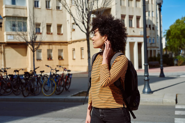 Cute young black woman walking alone with a backpack during the day - Fotoğraf, Görsel