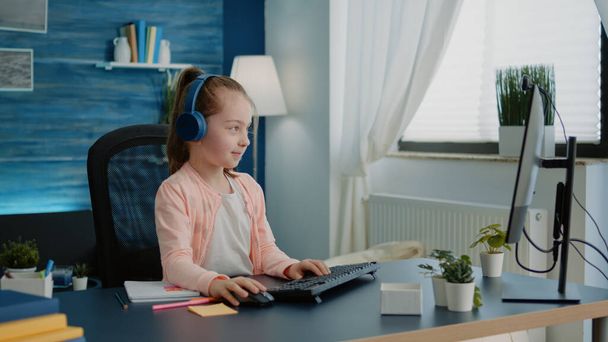 Ребенок машет на видео-звонок веб-камера на компьютере для школьной работы - Фото, изображение