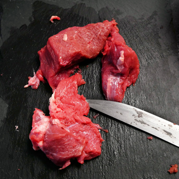 solomillo trozos de carne de ternera filete mignon en la pizarra negra. con cuchillo Vista superior. Primer plano. - Foto, imagen