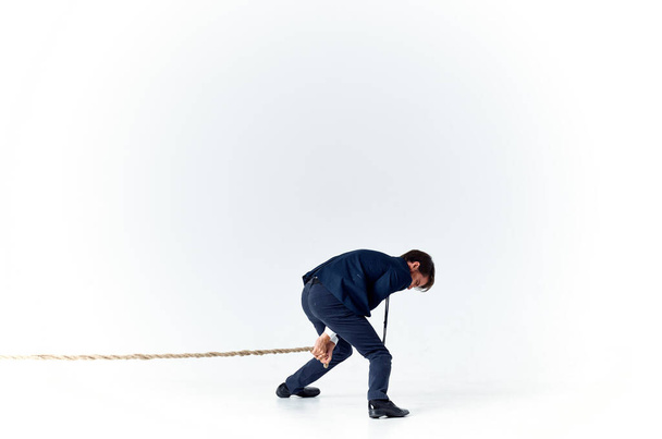 business man in a suit pulls the rope studio light background - Photo, Image