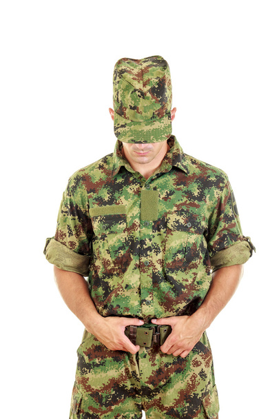 Military soldier in camouflage uniform and hat fastened belt - Фото, изображение