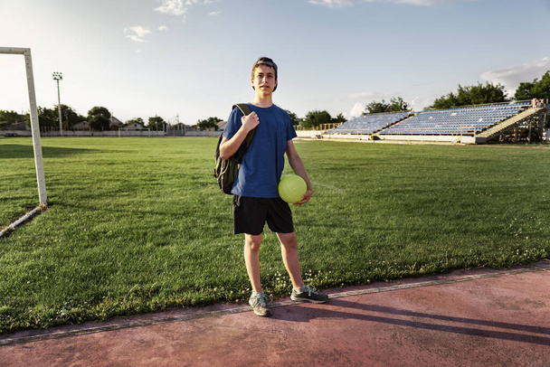 koncepció a sport és az egészség - tini fiú pózol egy stadionban, egy focipálya zöld fű. - Fotó, kép