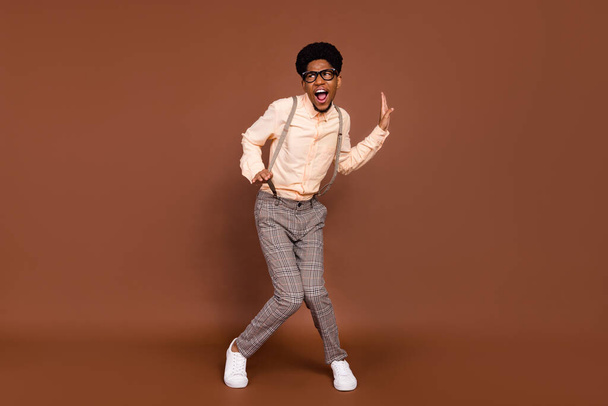 Full length body size view of attractive cheerful childish guy dancing having fun rest isolated over brown color background - Zdjęcie, obraz